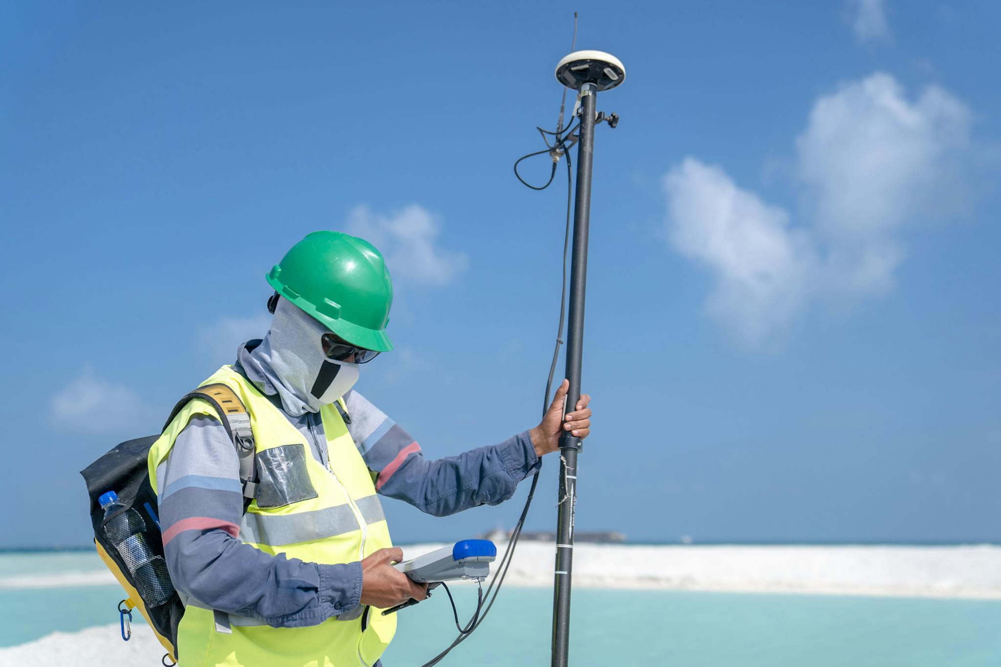 Surveyor using GPS equipment for land measurement outdoors under a clear sky.